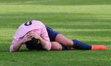 Ein Fußballer fasst sich an den Kopf, weil er Schmerzen hat (verweist auf: „Schädel-Hirn-Trauma im Sport“: Einzelne Vorträge der BISp-Fachtagung nun auf YouTube)