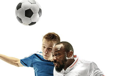 Das Bild zeigt zwei Männer, die in die Luft springen, um einen Kopfball beim Fußball auszuführen. (verweist auf: Kurzbeitrag der Sportschau zur Diskussion um das Spielen von Kopfbällen)